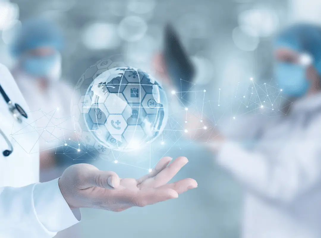 A doctor's hand hovers under a digital globe with healthcare icons, symbolizing technology in medicine. Blurred medical staff fills the background.